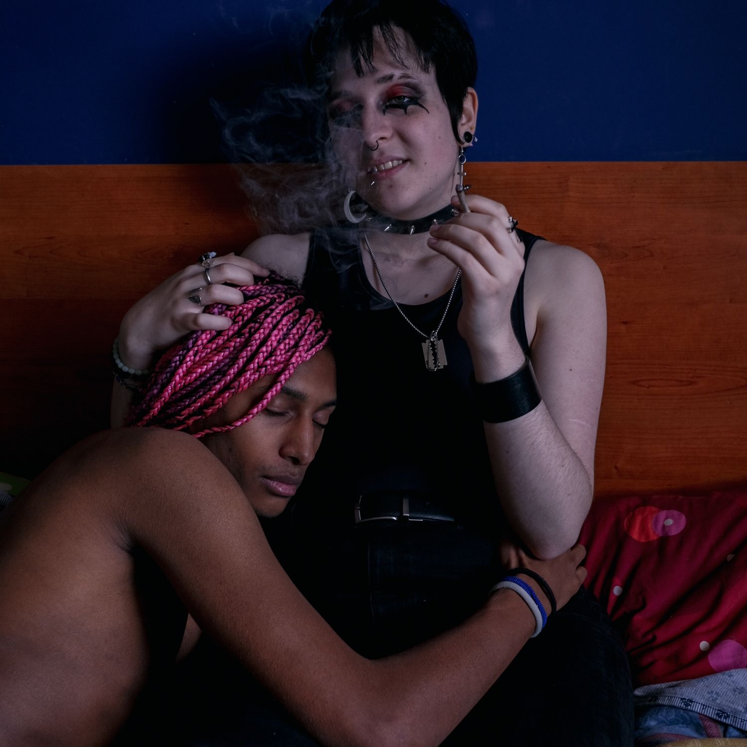 A person with pink braids resting against another person