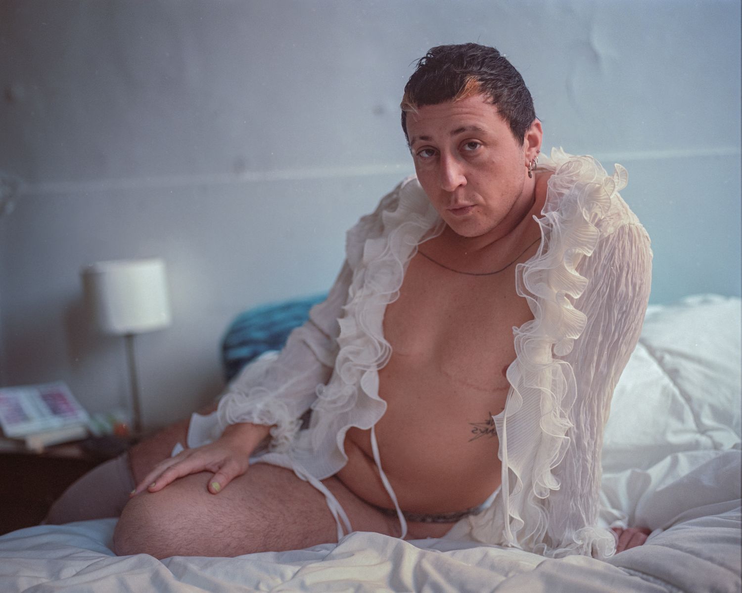 A person in a white ruffled robe sitting on a bed