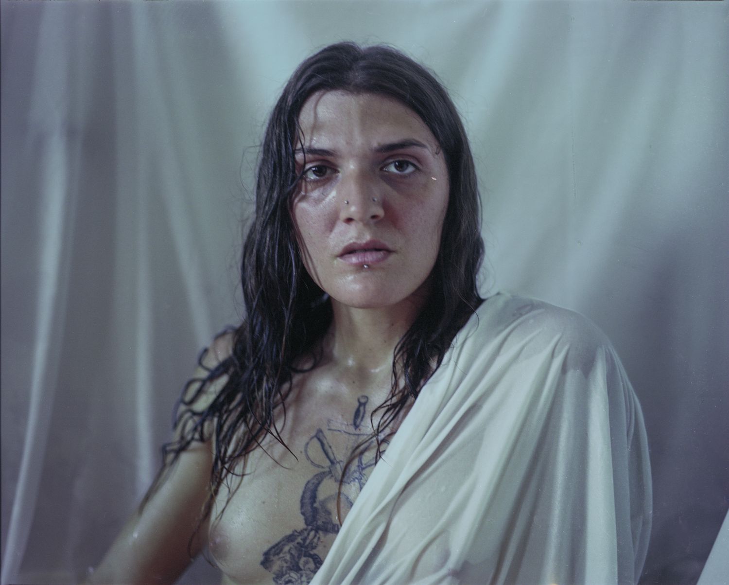 Portrait of a person with wet dark hair draped in white fabric